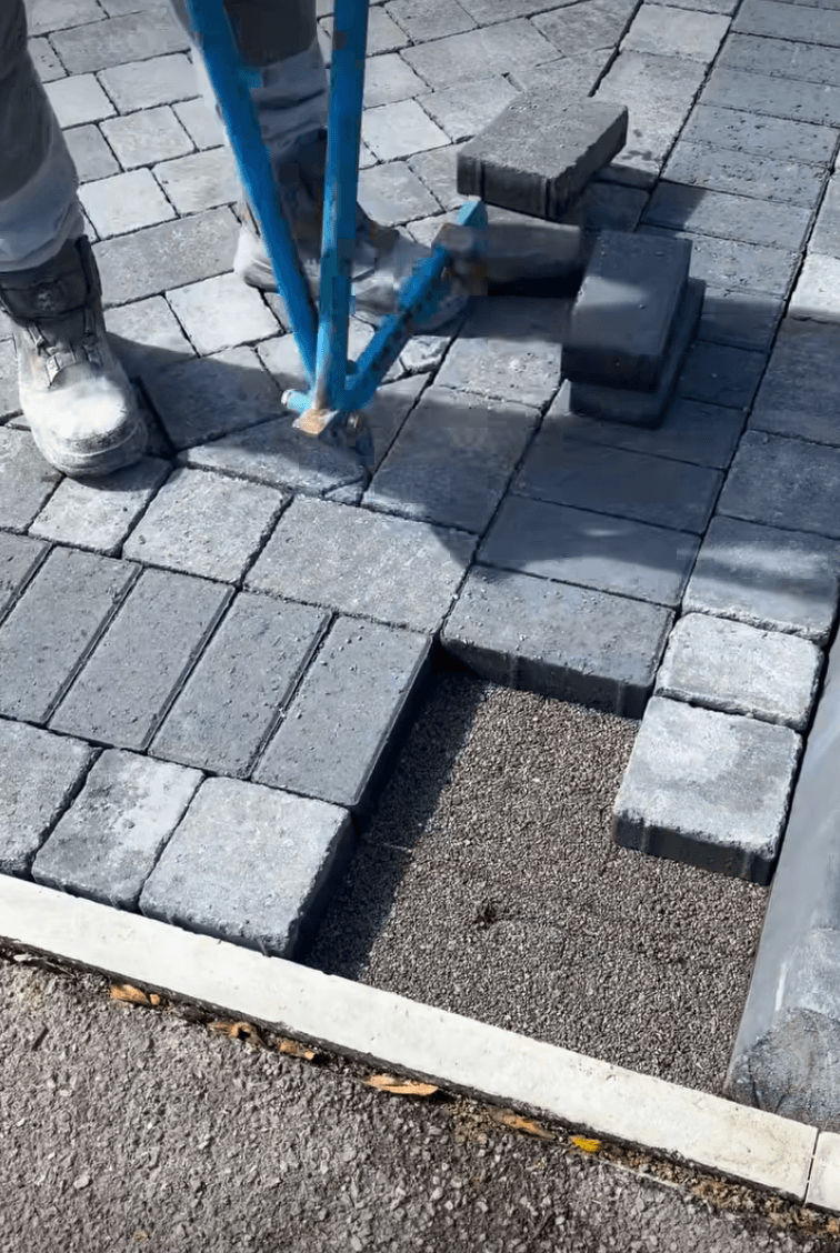 Setts being laid into a fresh block paving pattern with a rubber mallet on the ground.